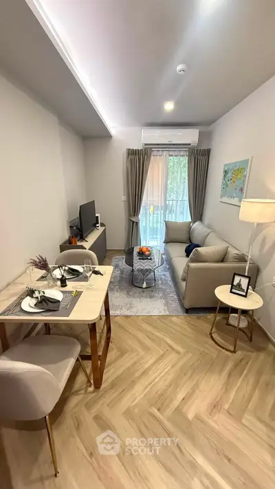 Modern living room with cozy seating and stylish decor, featuring a dining area and natural light from balcony.