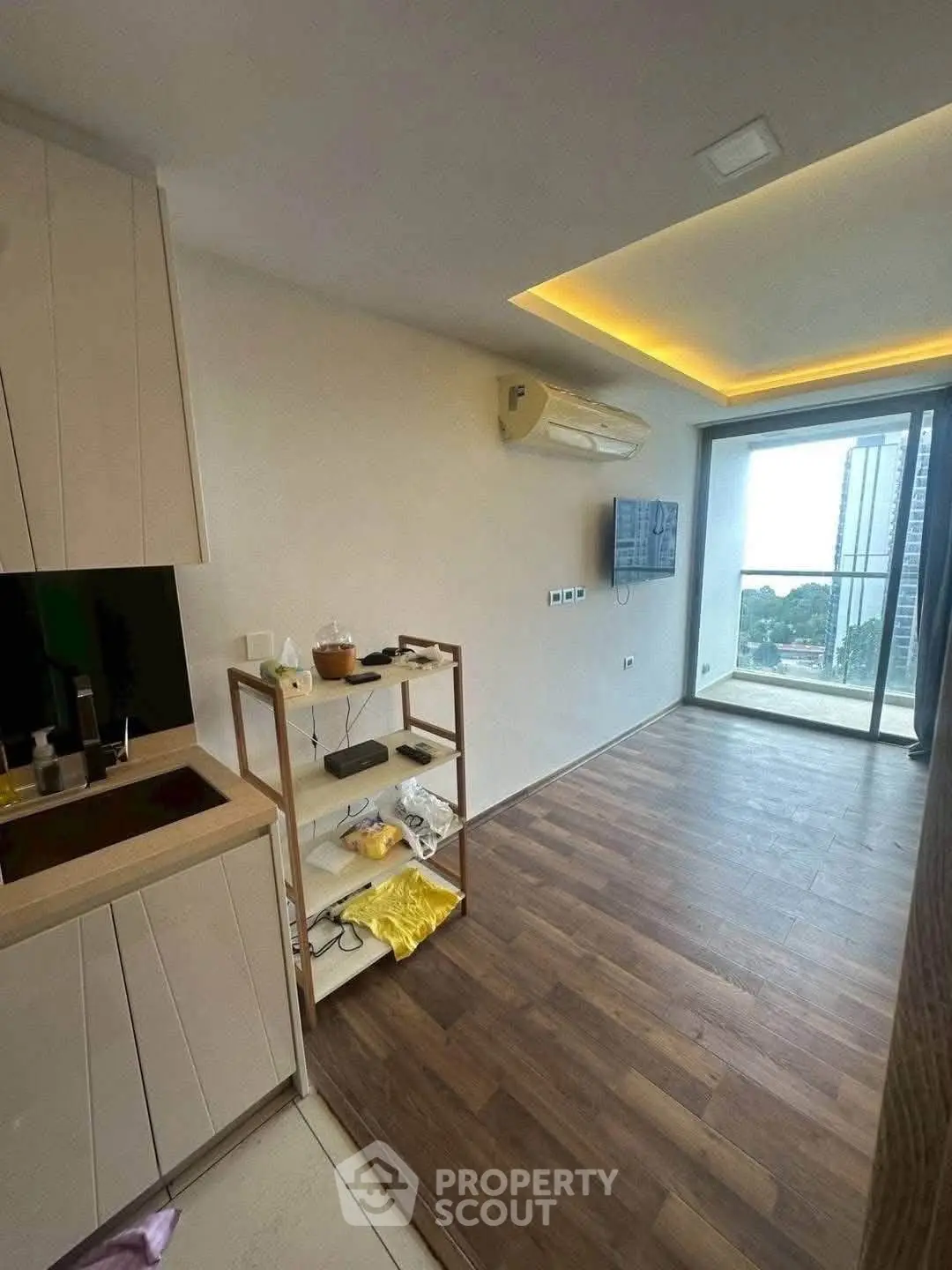 Modern living room with wooden flooring, air conditioning, and balcony view in a stylish apartment.