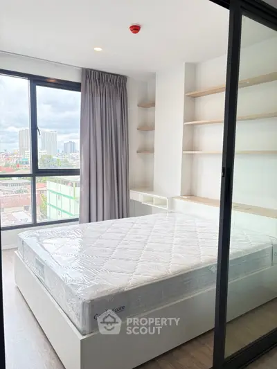 Modern bedroom with large window and built-in shelves in a high-rise apartment.