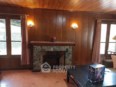 Charming rustic living room with wooden paneling and stone fireplace, perfect for cozy gatherings.