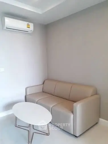 Modern living room with sleek sofa and air conditioning in a minimalist design.