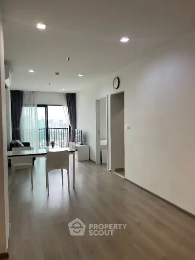 Spacious modern living room with balcony and city view, featuring sleek furniture and natural light.