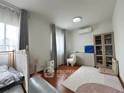 Spacious bedroom with wooden flooring, large windows, and modern furnishings.