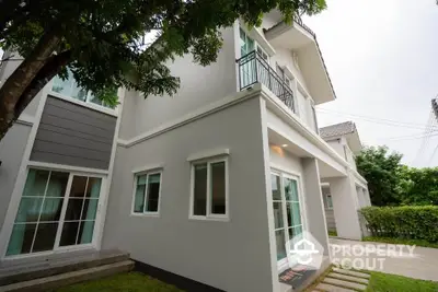 Modern two-story house with balcony and lush greenery