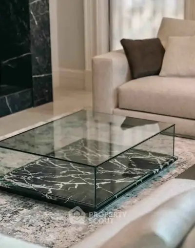 Elegant living room with modern glass and marble coffee table and plush sofa.