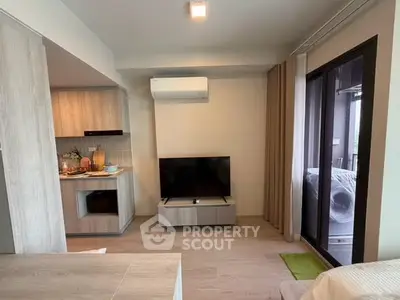 Modern living room with open kitchen and balcony access in stylish apartment.