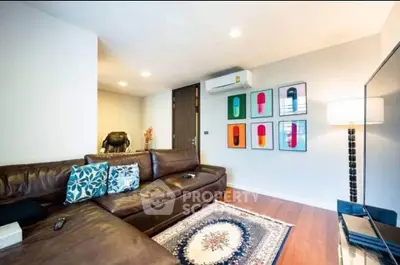 Modern living room with leather sofa, stylish decor, and wooden flooring.
