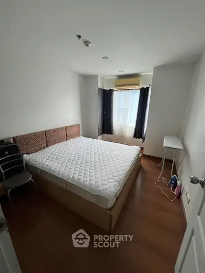 Spacious bedroom with large window and wooden flooring, featuring a comfortable bed and modern decor.