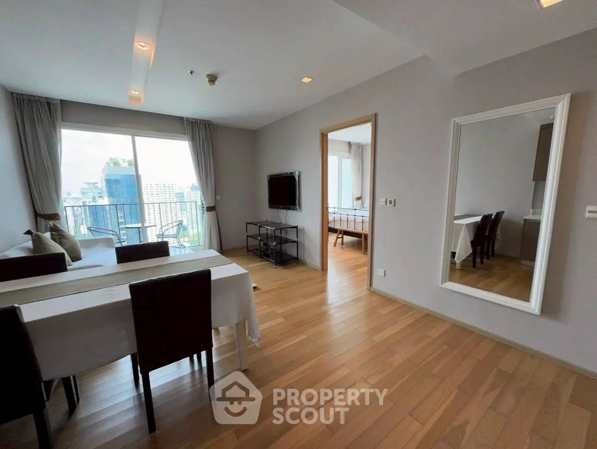 Spacious modern living room with dining area and city view, featuring elegant wooden flooring.