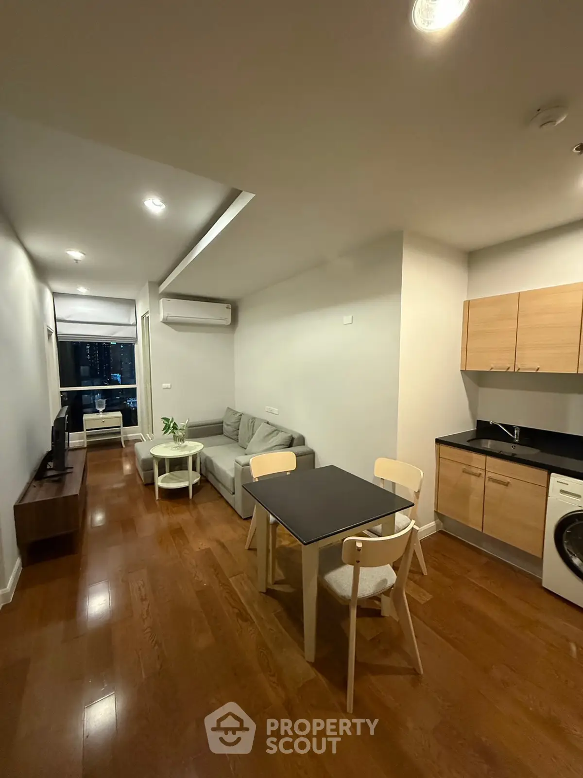 Modern living room with open kitchen and wooden flooring in a cozy apartment.