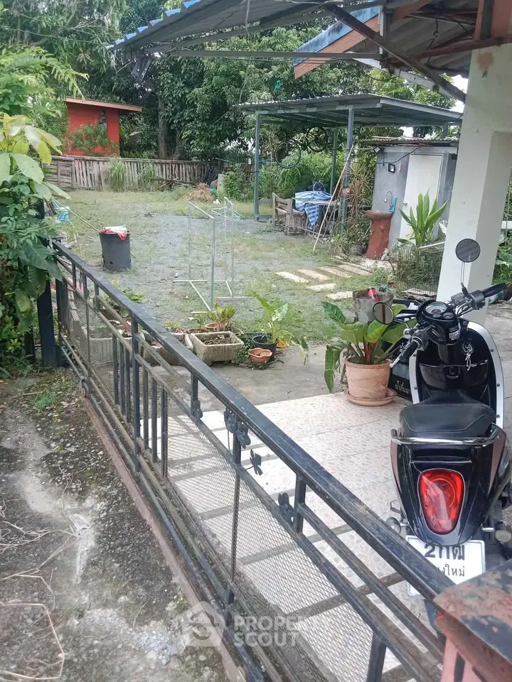 Charming outdoor space with lush greenery and covered parking area, ideal for relaxation.