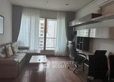 Modern living room with sleek furniture and large window offering natural light.