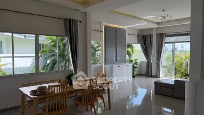 Spacious dining area with large windows and lush garden view, perfect for family gatherings.