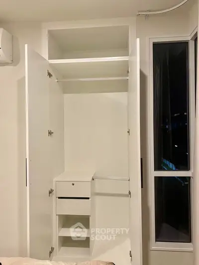 Spacious white wardrobe with open doors in modern apartment bedroom.