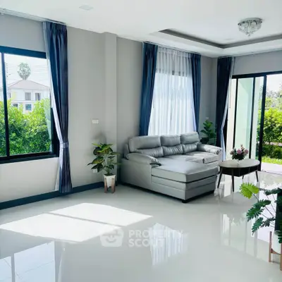 Spacious living room with modern sofa and large windows offering abundant natural light.