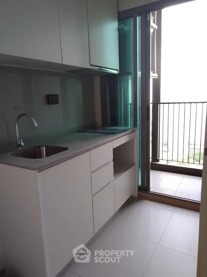 Modern kitchen with sleek cabinetry and balcony access in a high-rise apartment.