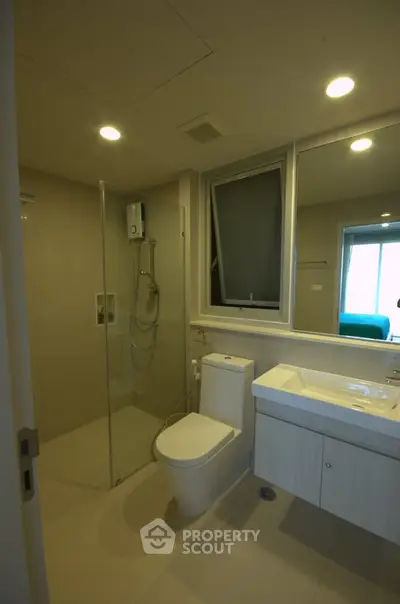 Modern bathroom with glass shower and sleek fixtures in contemporary apartment.