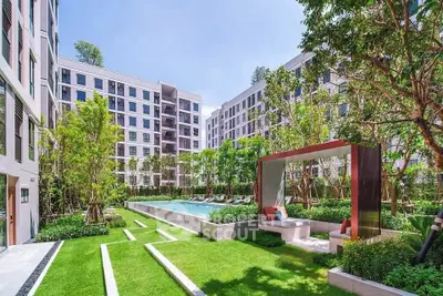 Luxurious apartment complex with lush garden and inviting pool area, perfect for relaxation and leisure.