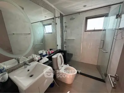 Modern bathroom with glass shower, round mirror, and sleek fixtures in a contemporary home.