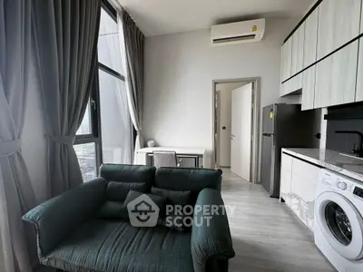 Modern apartment interior with stylish living room and kitchen featuring washing machine and large windows.