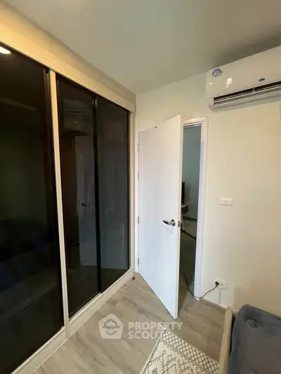 Modern bedroom with sleek wardrobe and air conditioning unit, showcasing contemporary design and comfort.