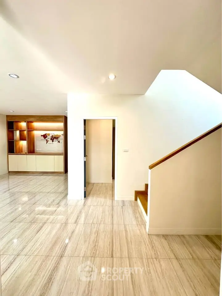 Spacious modern interior with elegant staircase and built-in shelving, perfect for stylish living.