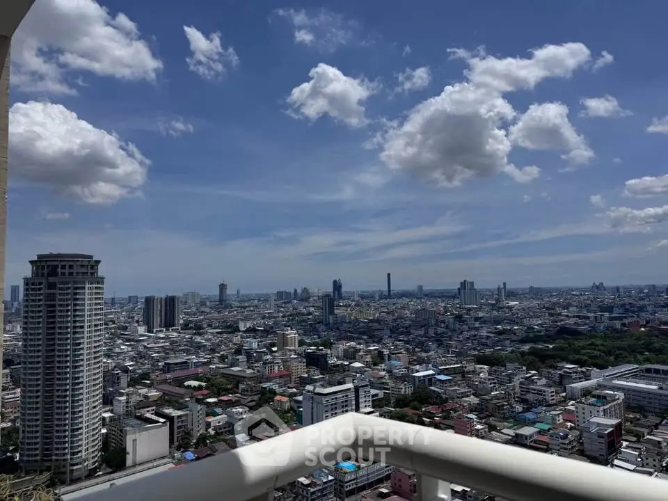 Stunning cityscape view from high-rise balcony under a vibrant blue sky.