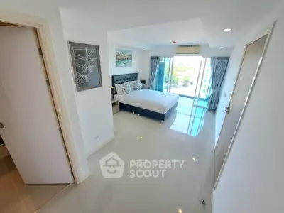 Spacious modern bedroom with large windows and balcony access, offering a bright and airy atmosphere.