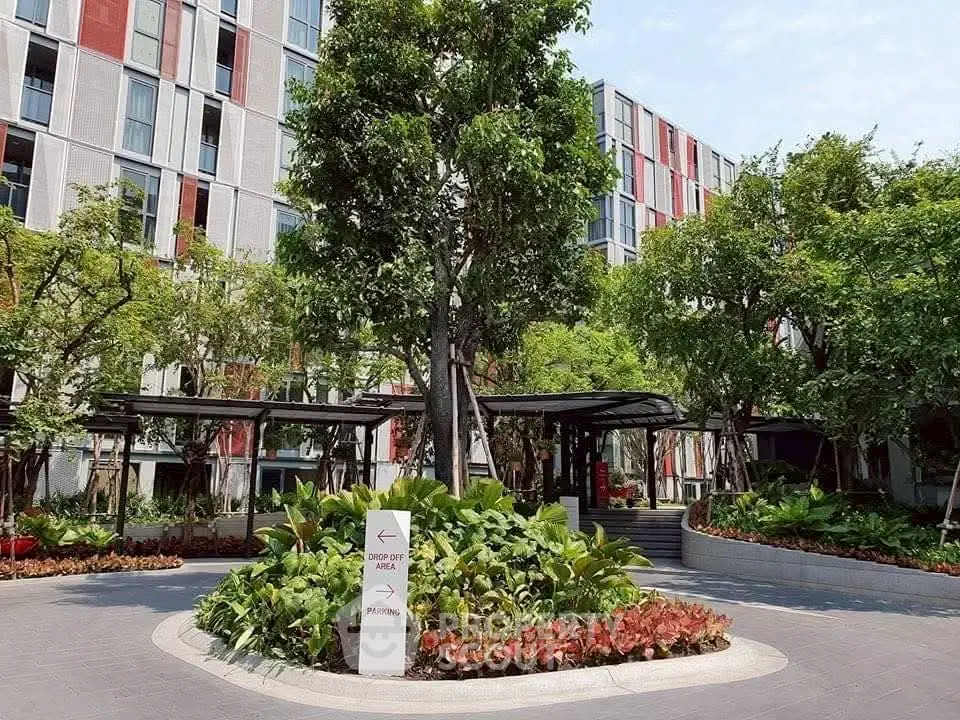 Modern residential building with lush landscaped garden and drop-off area.