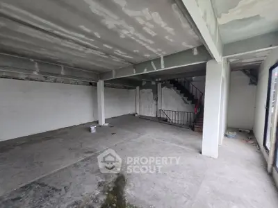 Spacious unfinished interior with concrete floors and staircase, ideal for customization.