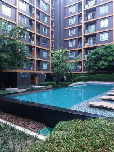 Luxurious residential complex with a serene pool area surrounded by lush greenery and modern apartment facades, offering a tranquil urban retreat.