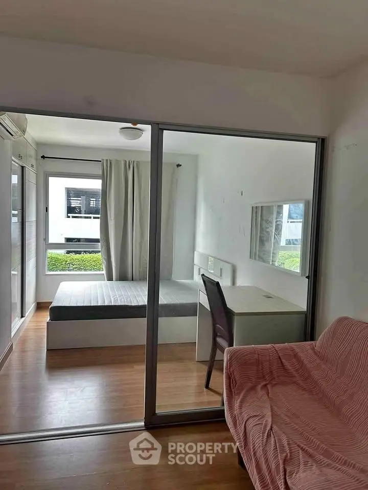 Modern bedroom with glass partition, cozy bed, and study desk in a bright apartment.