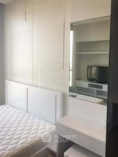 Modern bedroom with sleek design, featuring a built-in wardrobe and a cozy TV nook.