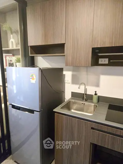 Modern kitchen with sleek cabinetry and stainless steel fridge in compact layout.