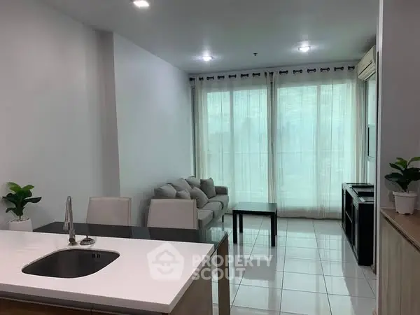 Modern open-layout living room with kitchen island and sleek furnishings.