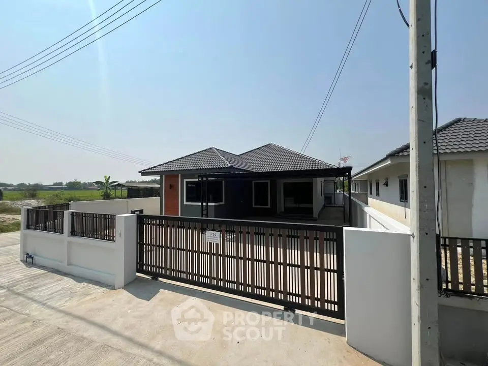 Modern single-story house with gated entrance and spacious driveway in a serene neighborhood.