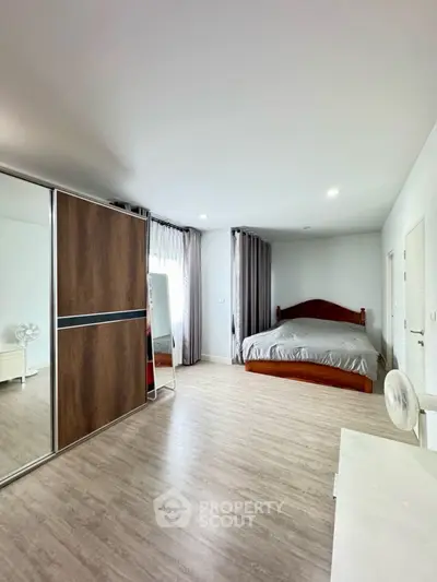 Spacious bedroom with modern wooden flooring and large wardrobe