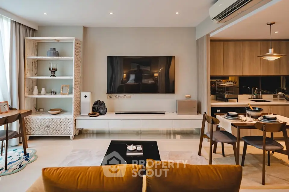 Modern living room with open kitchen, stylish decor, and large wall-mounted TV.