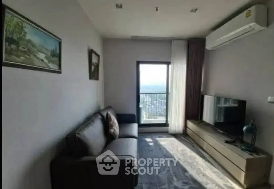 Modern living room with balcony view, featuring sleek furniture and air conditioning.