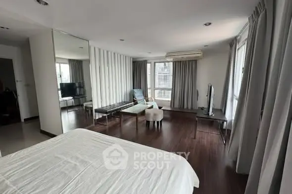 Spacious modern bedroom with elegant decor and large windows offering natural light.