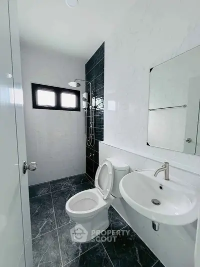Modern bathroom with sleek fixtures and marble tiles, featuring a shower and toilet.