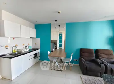 Modern open-layout kitchen and living area with vibrant blue accent wall and cozy seating.