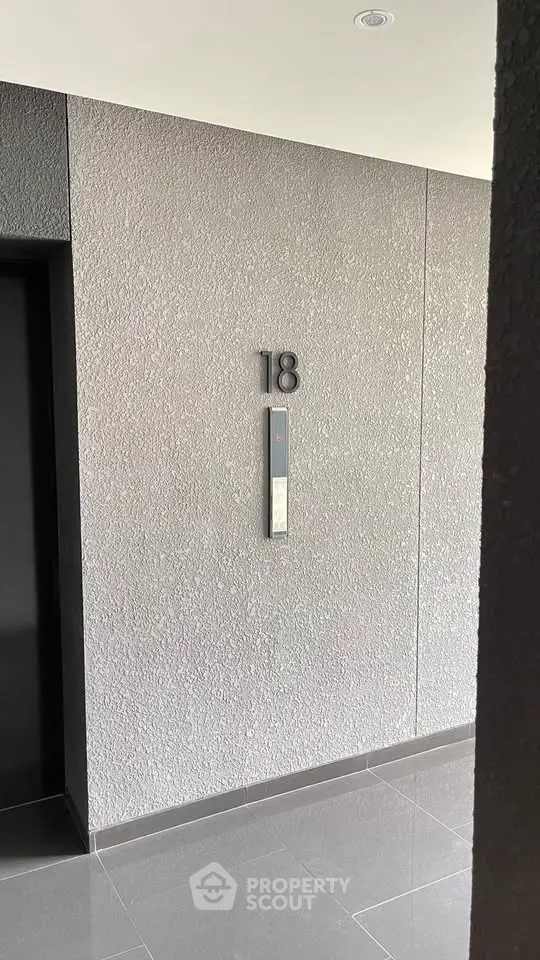 Modern building corridor with sleek elevator and floor number signage.