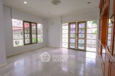 Spacious living room with large windows and marble flooring in a bright home.