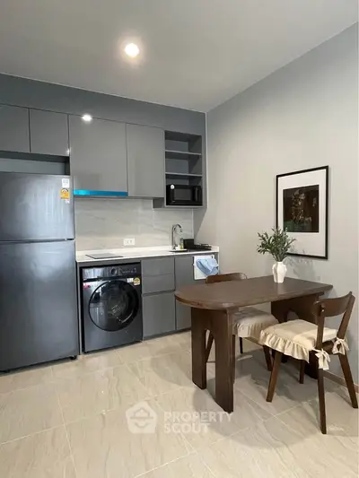 Modern kitchen with sleek cabinetry, washing machine, and cozy dining area in stylish apartment.