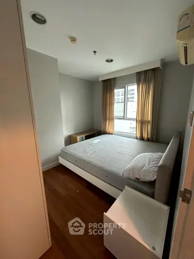 Cozy bedroom with natural light and modern furnishings in urban apartment.