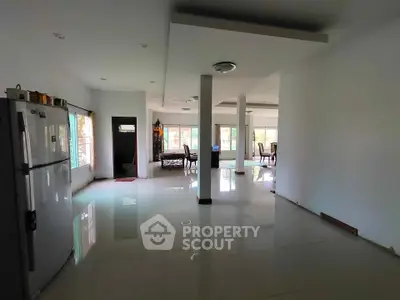Spacious open-plan living area with modern kitchen and dining space, featuring large windows for natural light.