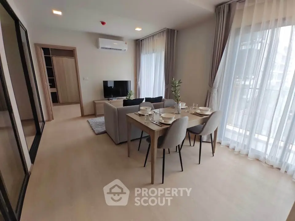 Modern living room with dining area and large windows in a stylish apartment.