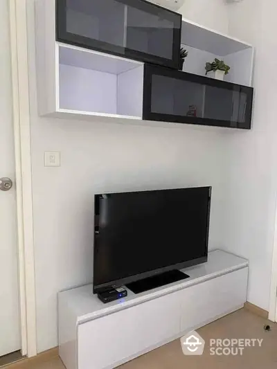 Sleek modern living room with wall-mounted shelves and a large flat-screen TV, perfect for cozy entertainment.