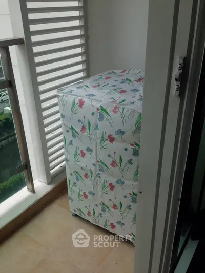 Charming small balcony with floral-patterned washing machine cover, perfect for urban living.